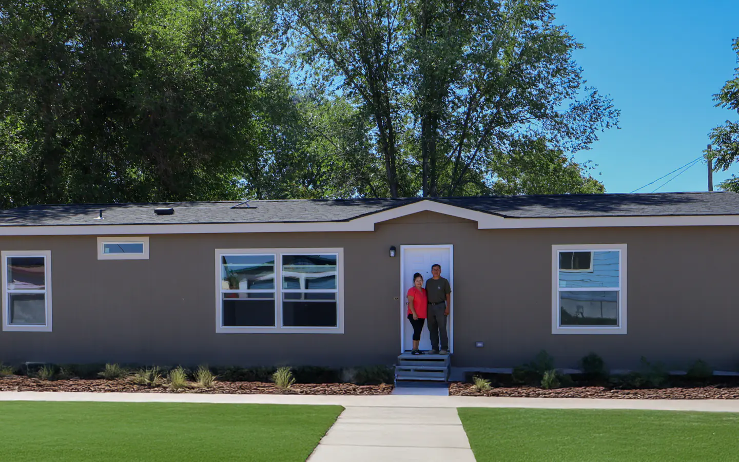 Manufactured-home owners standing at their completed home
